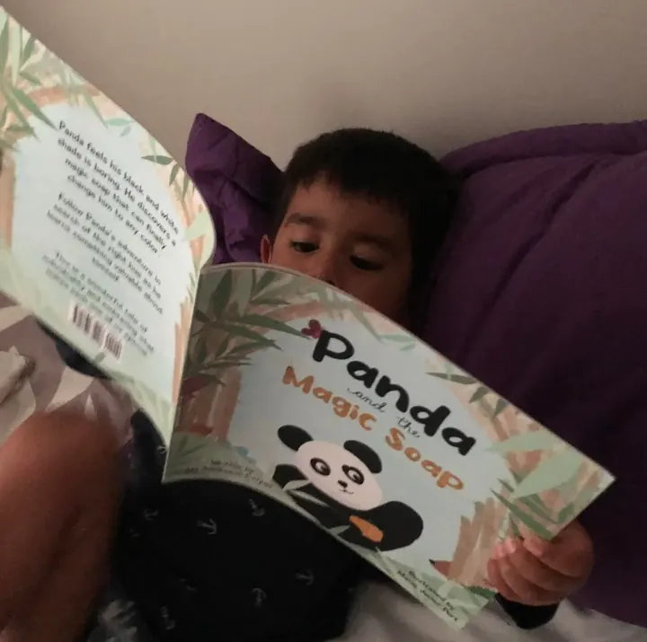 A boy reading Panda and the Magic Soap in bed
