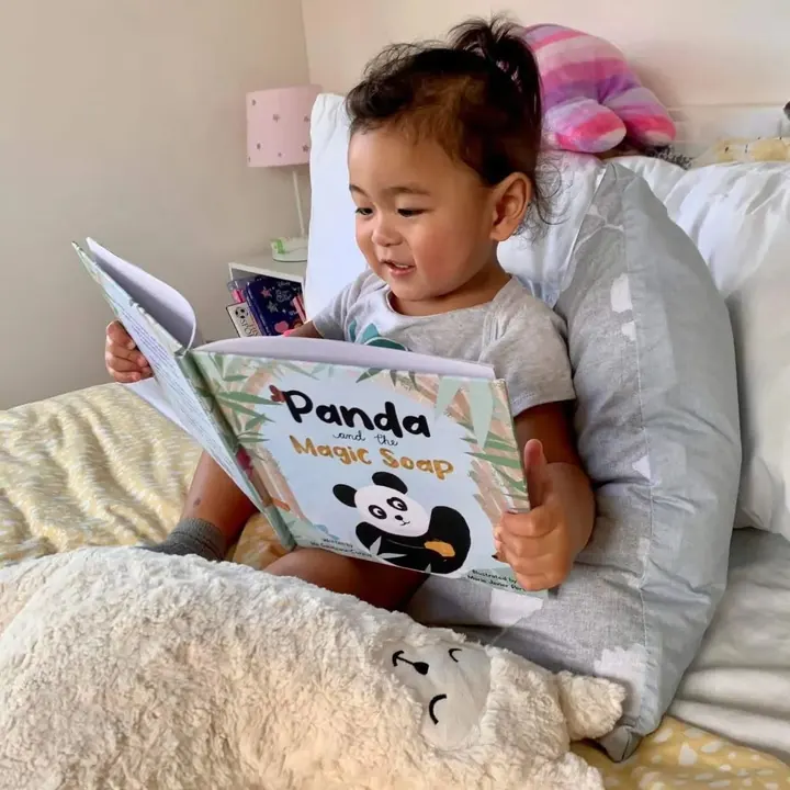 A toddler reading Panda and the Magic Soap in bed