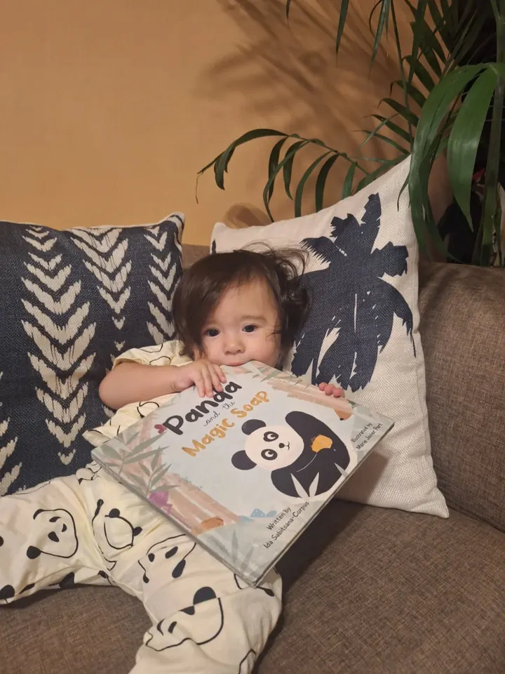 A baby holding the book close, taking a bite of the cover
