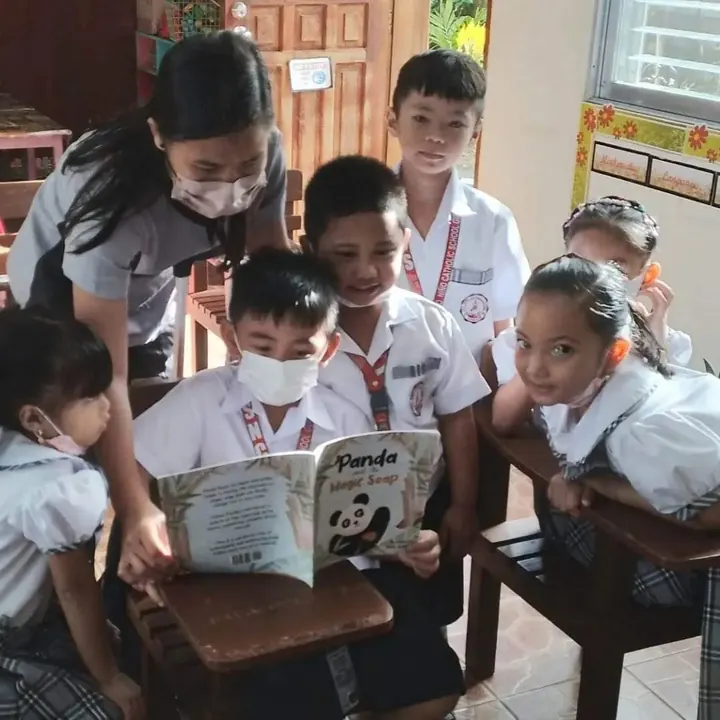 Schoolchildren in Guimaras reading Panda and the Magic Soap with their teacher