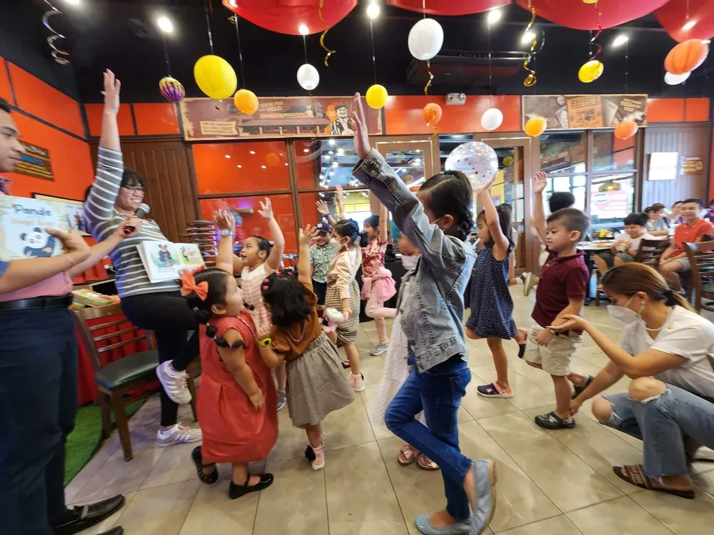 Ida leading a Panda story time with kids dancing along