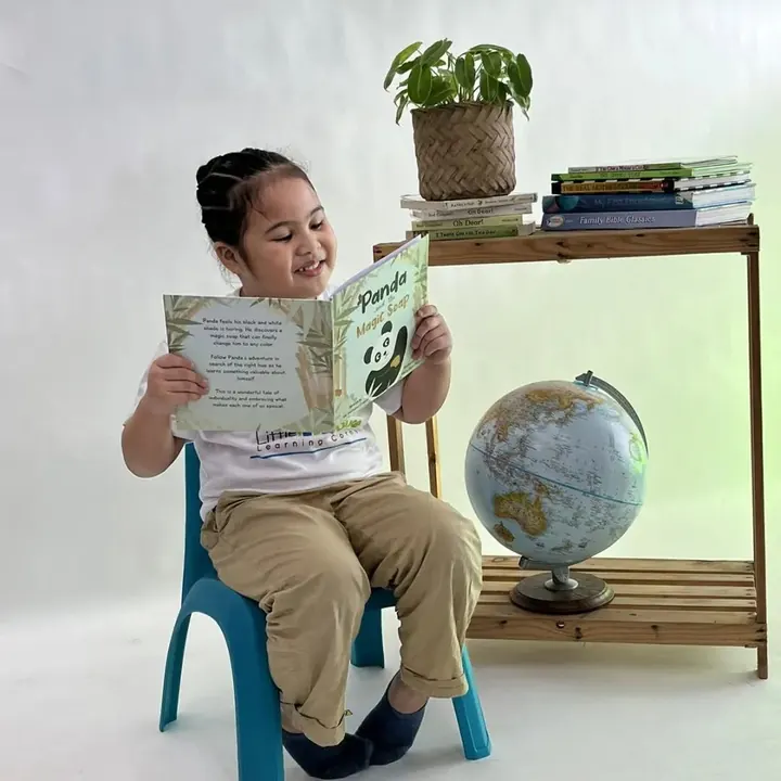 A girl at Little House Learning Center reading the back cover