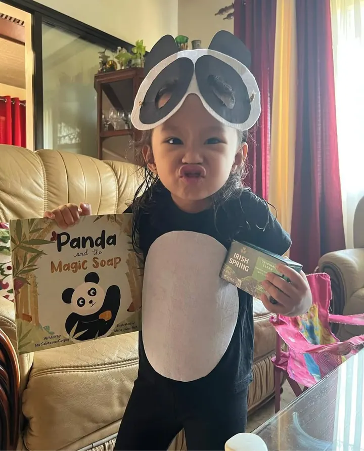 A little girl dressed as Panda, holding the book and a bar of soap