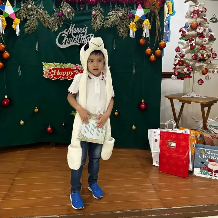 A boy in a panda hood holding the book at a Christmas party